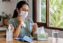 Rondônia fica fora do alerta atual, mas prevenção contra vírus respiratórios deve continuar Mulher de máscara verifica a temperatura em casa com álcool em gel e itens de prevenção sobre a mesa