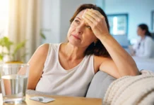 Anvisa aprova remédio sem hormônios para ondas de calor da menopausa Mulher com ondas de calor da menopausa segura compressa enquanto medicamento não hormonal aparece sobre a mesa