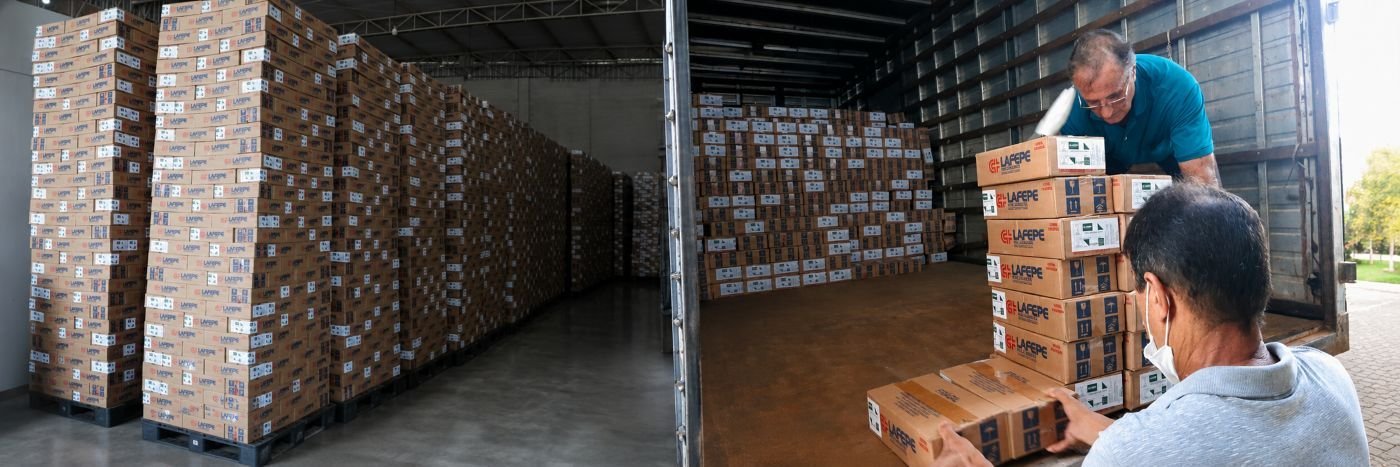 Caixas de medicamentos empilhadas em armazém e sendo carregadas em caminhão para distribuição