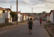Cacoal abre inscrições para o Minha Casa, Minha Vida de 29 de junho a 15 de julho Rua com casas populares organizadas e família caminhando, representando inscrições para o Minha Casa Minha Vida em Cacoal.
