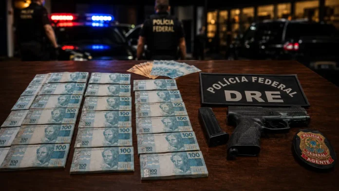 Dinheiro apreendido, arma, distintivo e identificação da Polícia Federal em operação contra tráfico interestadual de drogas