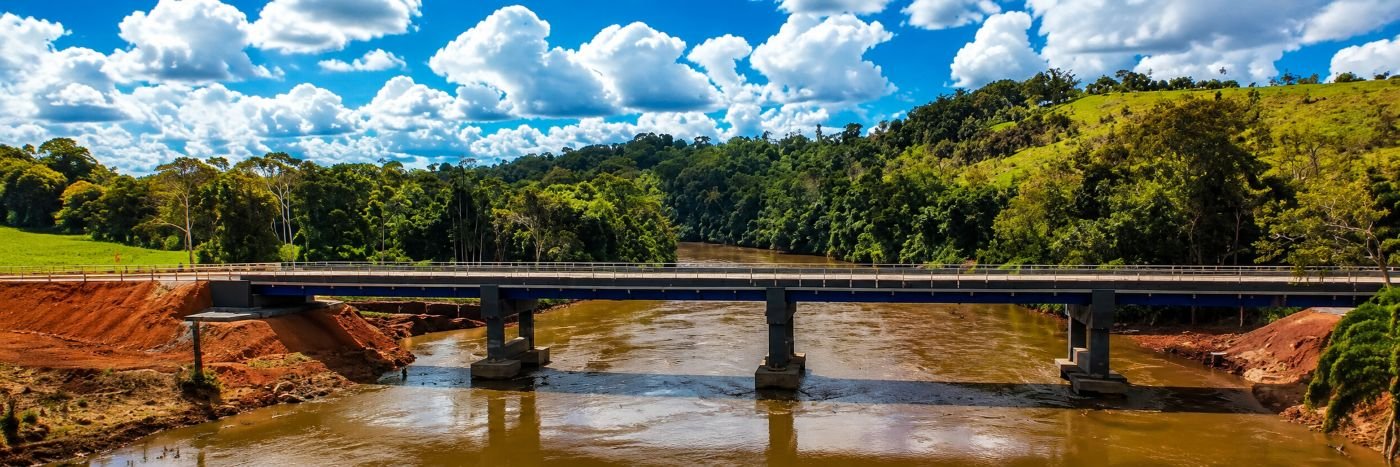 Ponte RO-495 sobre o Rio Pimenta Bueno aparece em imagem panorâmica com rio, vegetação e paisagem rural no Cone Sul de Rondônia.