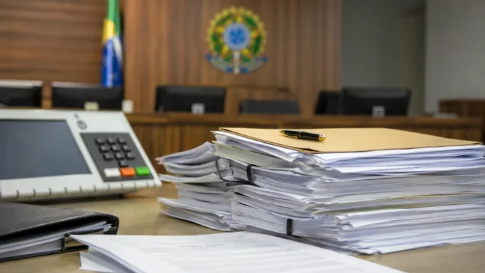 Documentos judiciais e urna desfocada representam decisão sobre assédio eleitoral em Ji-Paraná