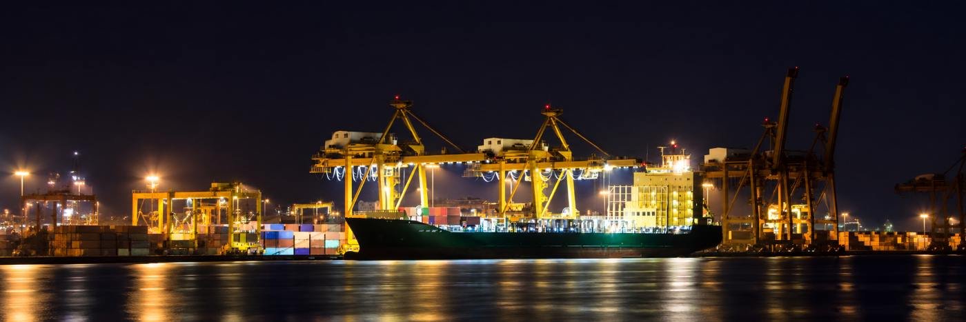 Navio cargueiro em porto iluminado à noite, representando logística internacional e exportações de carne bovina brasileira.