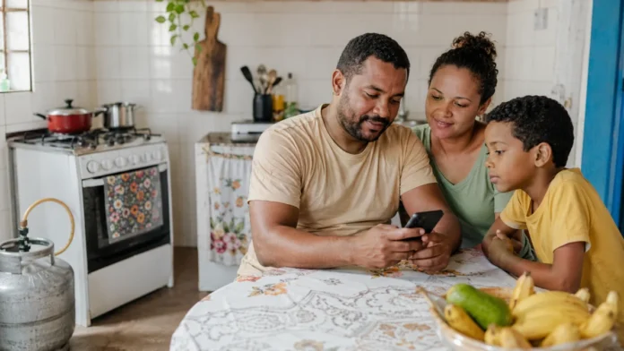 Família brasileira em cozinha simples consulta celular sobre o Gás do Povo em Rondônia