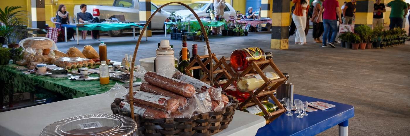 Mesa com produtos artesanais, alimentos caseiros e itens de pequenos empreendedores durante feira em Porto Velho.