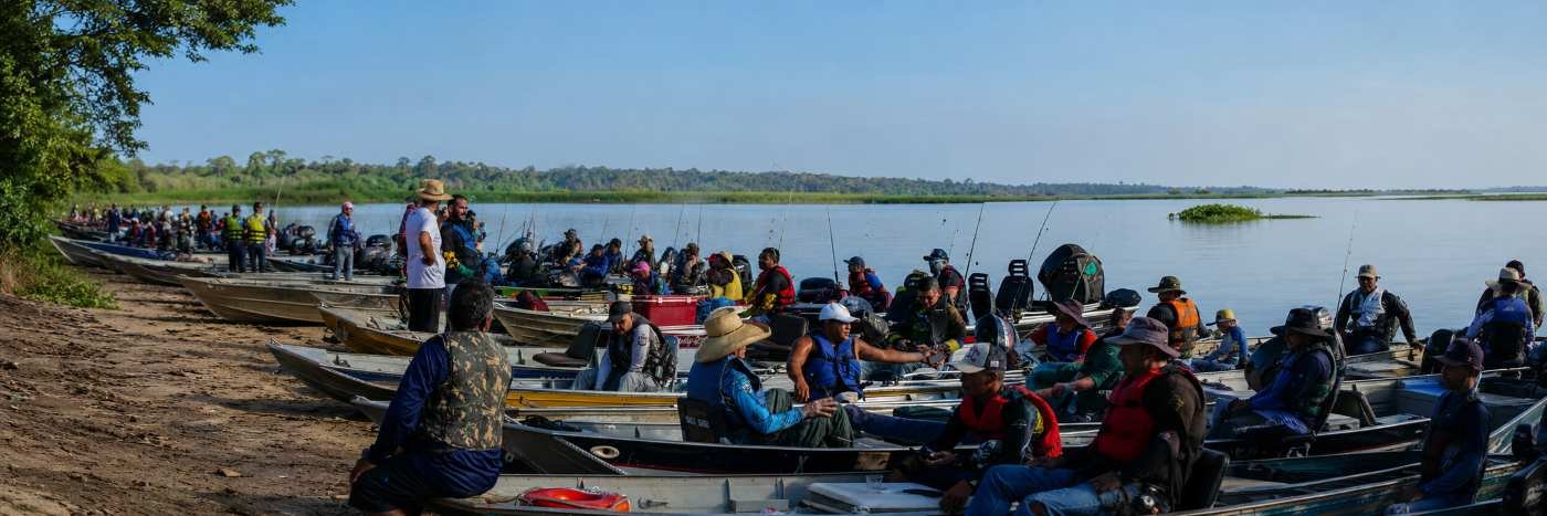 Barcos e pescadores reunidos em rio amazônico para atividade de pesca esportiva sustentável em Porto Velho