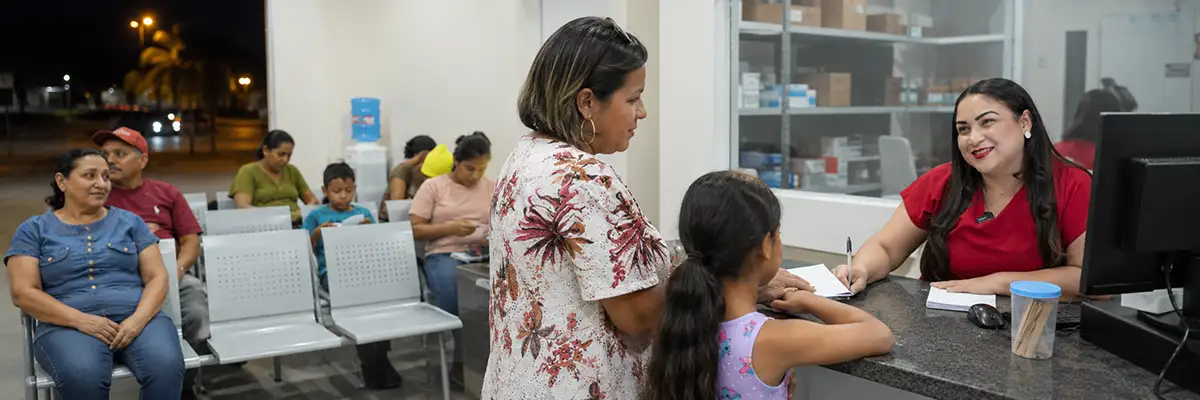 Corujão da Saúde Porto Velho com mulher e criança sendo atendidas e moradores aguardando na recepção noturna.