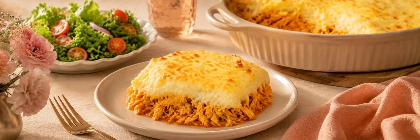 Porção de escondidinho de frango cremoso servida com salada verde