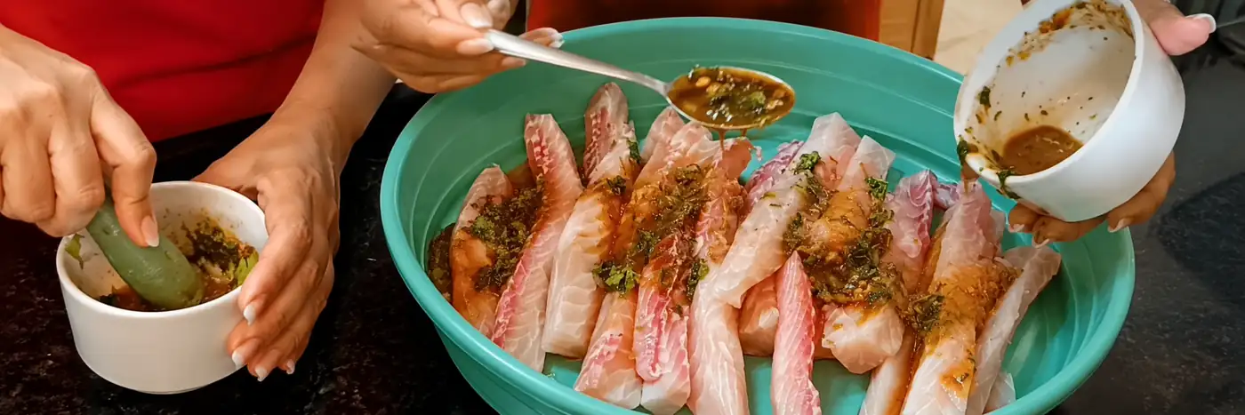 Tempero do lombo de peixe com molho de laranja sendo distribuído sobre o peixe