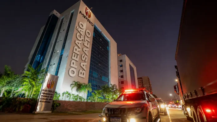 Sede do MPRO à noite com viatura e intervenção editorial Operação Basalto na fachada