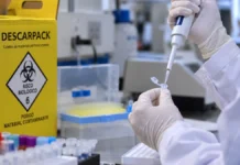 IFRO recebe sugestões até 2 de outubro para protocolo sobre acidentes com material biológico Consulta pública do IFRO: ilustração de mãos com luvas manipulando amostra em bancada laboratorial e coletor de perfurocortantes