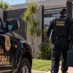 PF cumpre 15 mandados em investigação sobre contratos da Educação de Ji-Paraná Operação Página Virada ilustrada por composição de policiais diante de imóvel; imagem não documental.