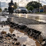 Asfalto cortado, prejuízo depois: lei cobra reparo e garantia de um ano em Porto Velho Reparo de ruas em Porto Velho com remendo afundado, água na pista, motociclista e carros